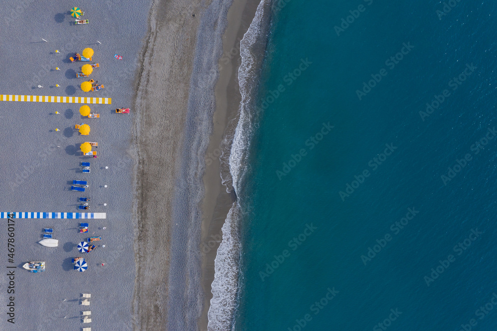Tourists sunbathing on Mediterranean pebble sea beach, aerial top view