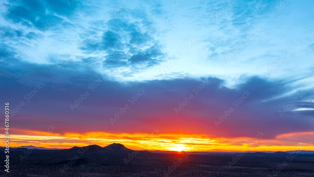 Watching the sunrise in colorful splendor as the sun flares over the Mojave Desert and warms the barren wilderness - aerial hyper lapse 