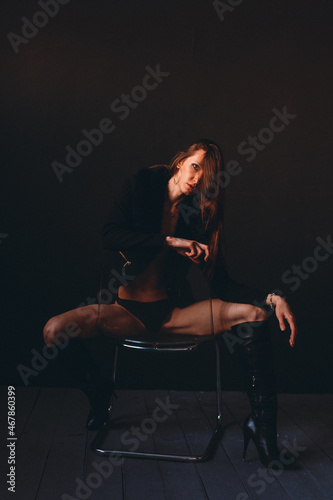 young beautiful girl, model appearance in a black bikini, high boots on her legs, in the studio on a black background