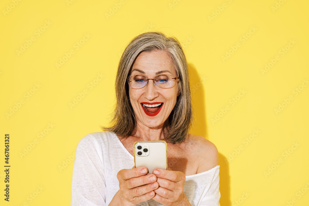 Mature woman in eyeglasses smiling while using mobile phone Mature woman in eyeglasses smiling while using mobile phone