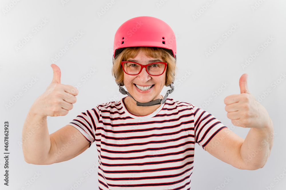 Elderly woman in ski helmet showing thumb up on white background.