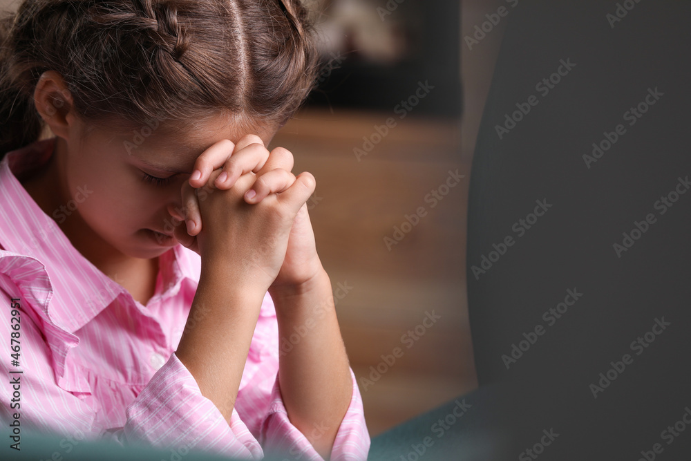 Cute little girl with hands clasped together praying indoors. Space for text Cute little girl with hands clasped together praying indoors. Space for text