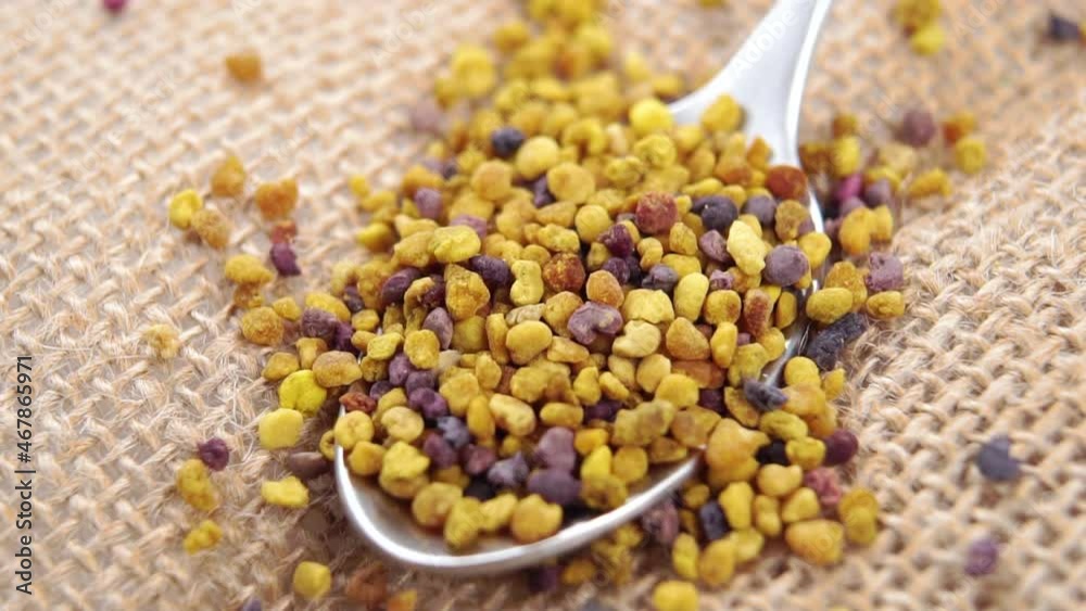 Healthy bee pollen grain falling into a spoon on a rustic burlap cloth in slow motion. Macro Healthy bee pollen grain falling into a spoon on a rustic burlap cloth in slow motion. Macro
