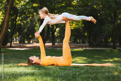 Happy mother lifting daughter on legs in park photo