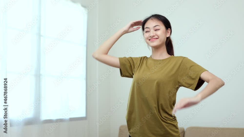 Attractive asian young fitness woman stretching arms warming up before workout at home. Beautiful smiling Female wearing sportswear exercise training yoga in living room.