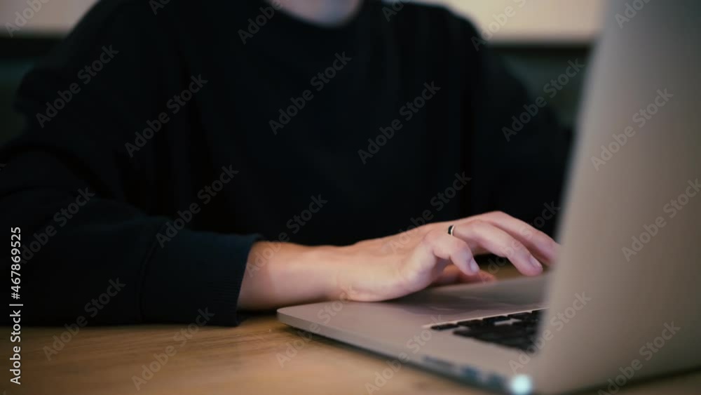 Close-up of hand typing on a laptop keyboard. A man in black clothes hacks into a website on a computer.