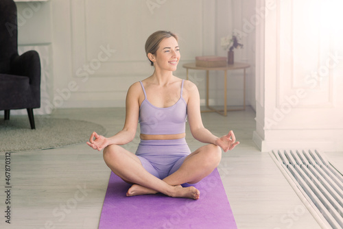 Young attractive smiling woman practicing yoga, working out, wearing sportswear, bra, home