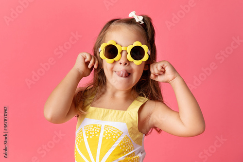 Silly little girl on pink background making funny face