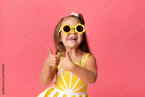 Funny little girl on pink background making funny face photo
