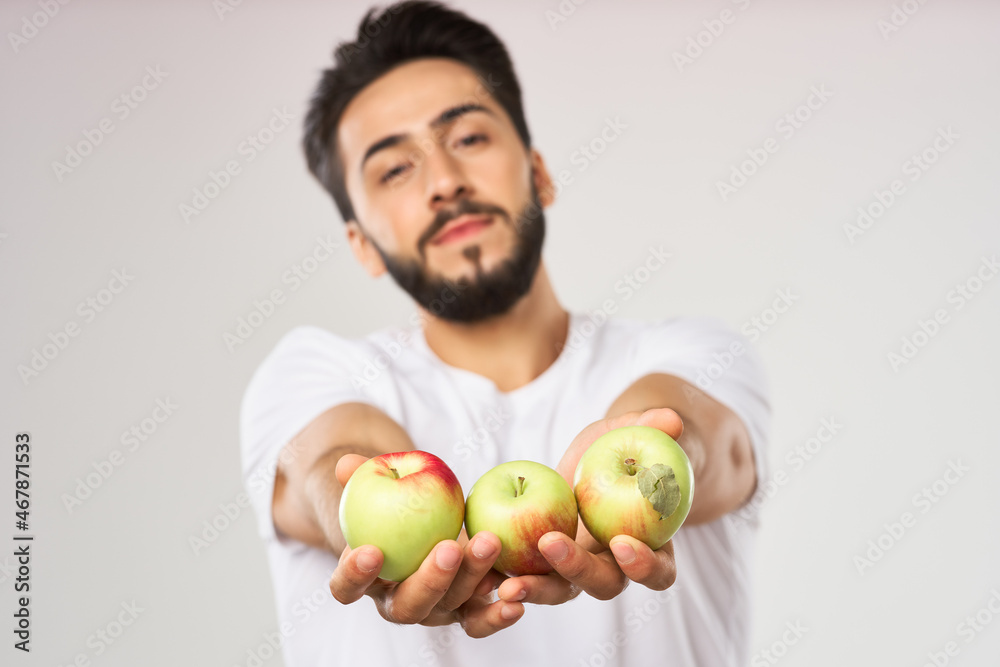Cheerful man with apples in his hands in a white t-shirt fruits Cheerful man with apples in his hands in a white t-shirt fruits