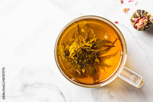 Green tea with flower ball in glass cup, white background.