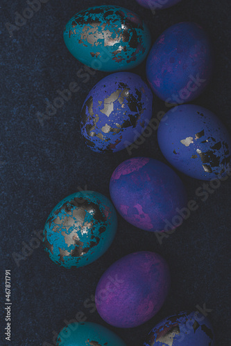 Easter eggs purple and blue with golds on dark background.