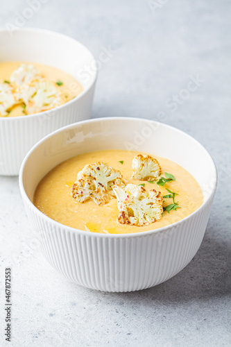 Vegetarian cream cheese soup with cauliflower in white bowl. Healthy vegan food concept.