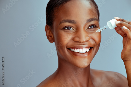 Black beauty woman dropping collagen serum moisturizer on face photo