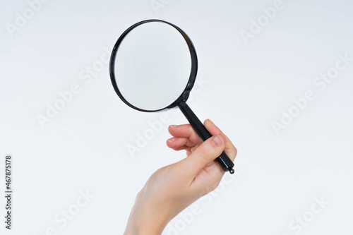 Woman hand with a magnifying glass. Magnifying glass close-up. Hand with a lens on a white background. A person's hand magnifies something. Magnifier with copy space. Magnifier as a symbol of audit.
