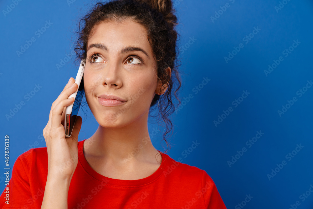 Young brunette woman with wavy hair smiling and talking on cellphone Young brunette woman with wavy hair smiling and talking on cellphone