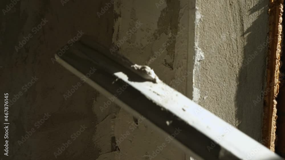 Close-up alignment of the plastered wall with a special construction tool. The concept of room finishing Close-up alignment of the plastered wall with a special construction tool. The concept of room finishing
