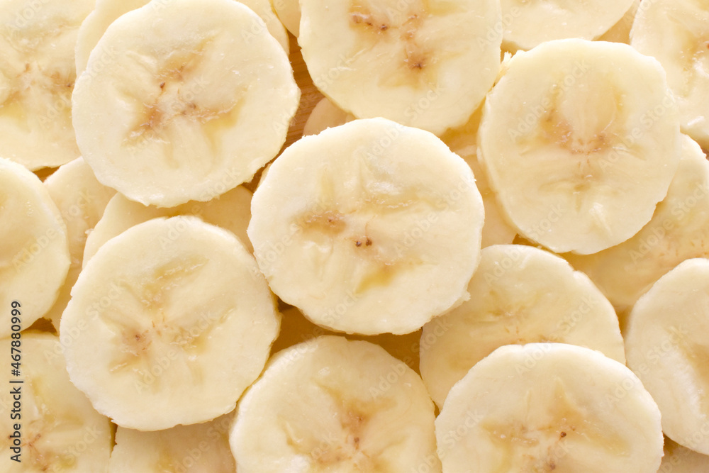 Banana slices on a bamboo chopping board texture background.  