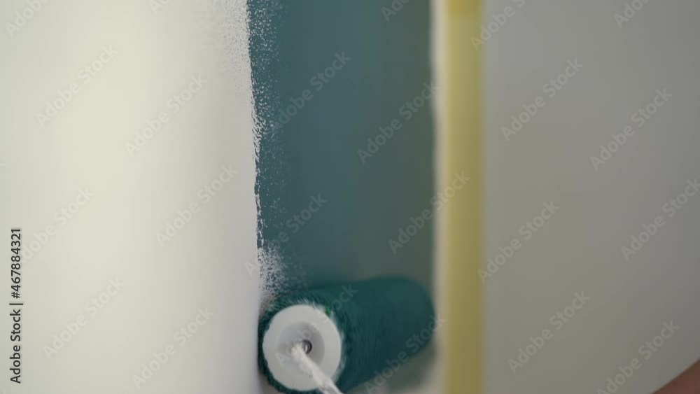 Painting a white wall in blue turquoise with a roller. Interior decoration, renovation and creativity Painting a white wall in blue turquoise with a roller. Interior decoration, renovation and creativity