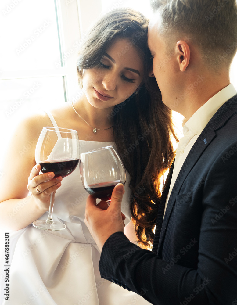 Young newlywed couple drinking wine and smiling at their happiness, romance and tenderness Young newlywed couple drinking wine and smiling at their happiness, romance and tenderness