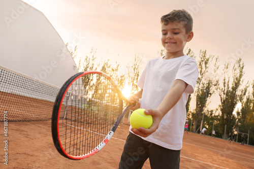 Cute little boy playing tennis on court outdoors © New Africa