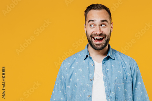 Young smiling happy amazed cheerful surprised caucasian man 20s in blue shirt white t-shirt look aside on workspace area isolated on plain yellow background studio portrait. People lifestyle concept. photo