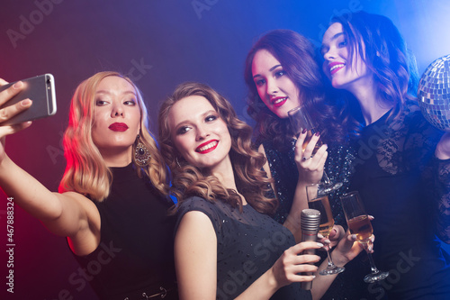 young women in luxury black dresses drinking champagne and having fun with karaoke, selfie and happy time.