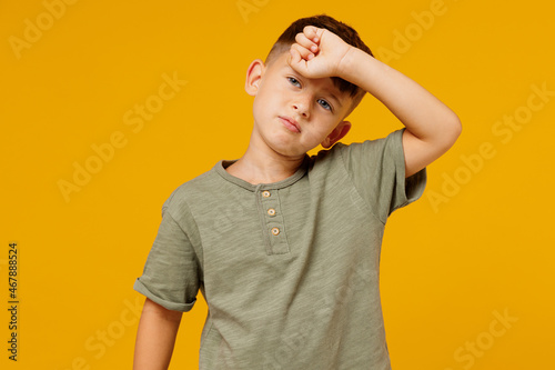 Murais de parede Little small tired sick ill happy boy 6-7 years old wearing green casual t-shirt put hand on forehead isolated on plain yellow background studio portrait