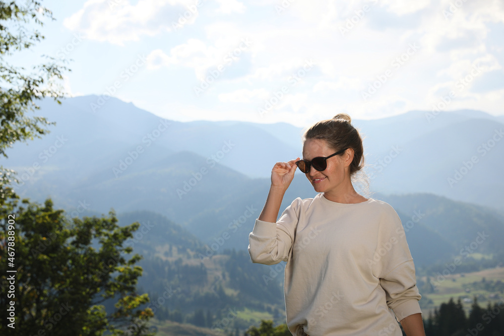 Woman with sunglasses in mountains. Space for text