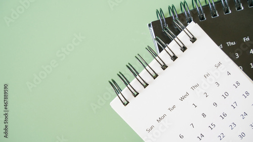top view of opened white calendar on black calendar with green background with copy space for meeting, appointment, timeline, timetable and due date concept