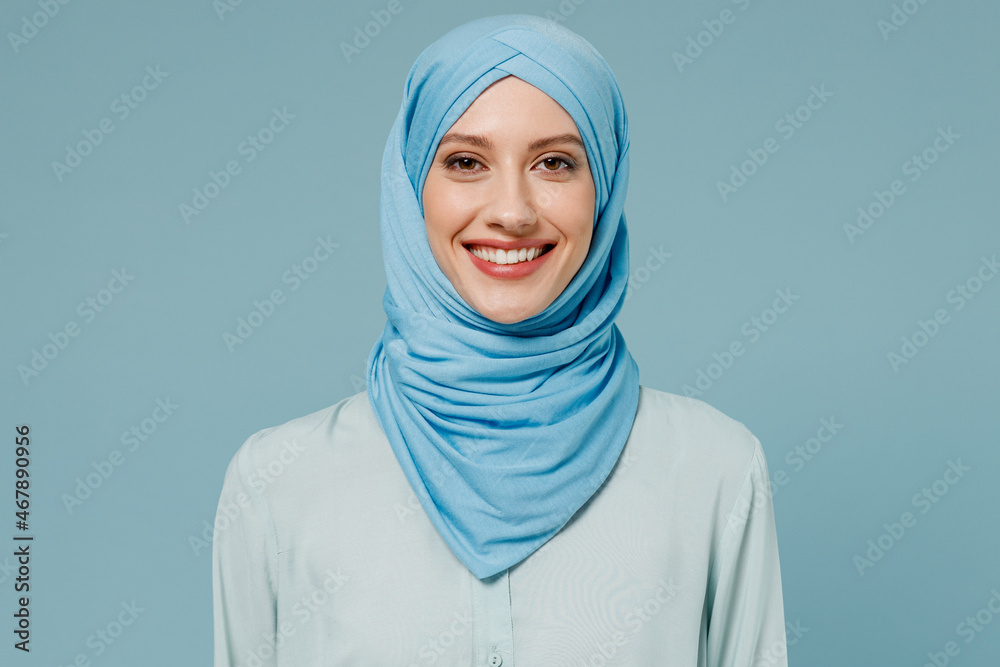 Young smiling calm confident arabian asian muslim woman in abaya hijab  clothes look camera isolated on plain blue color background studio  portrait. People uae middle eastern islam religious concept. Photos | Adobe