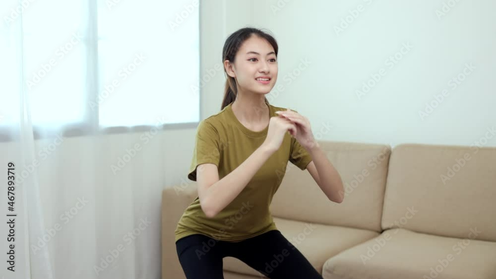 Young beautiful fitness asian woman doing squat sit up exercise workout at home. Attractive female warming up body training wearing sportswear. Side view Sporty girl stretching warm up cardio body.