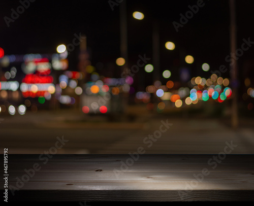 A dimly lit wooden table by the window in a pub opposite the abstract blurred lights of the night city. Selective focus
