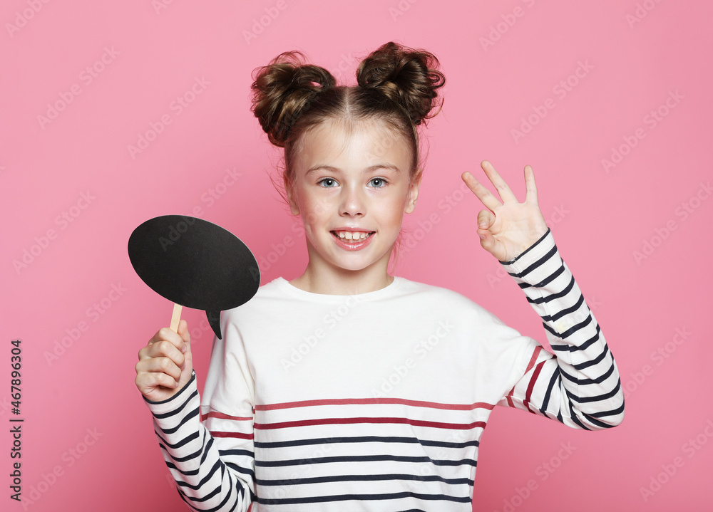 Photo of happy positive smart little girl holding empty paper mind cloud thinking over creative idea Photo of happy positive smart little girl holding empty paper mind cloud thinking over creative idea