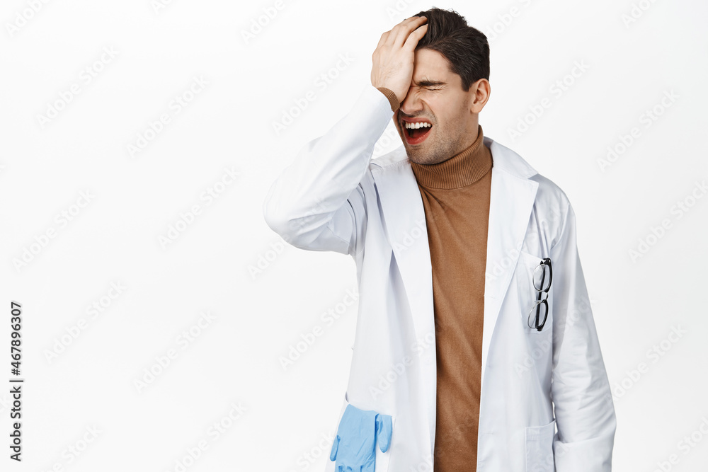 Frustrated doctor facepalm, disappointed in smth, making bad mistake, standing upset against white background, wearing medical uniform