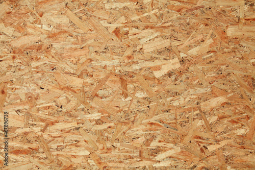 Wood (wooden) surface, texture, background. Building board made from pressed wood chips. A wall with a chaotic pattern created by press machines. Recyclable fence