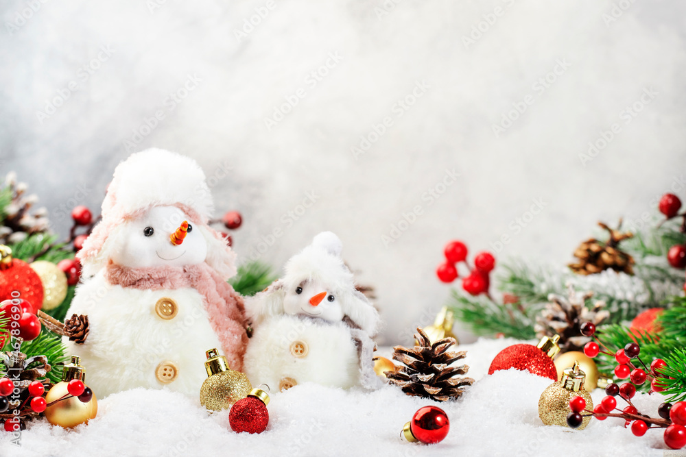 Christmas snow composition with two cute snowmen in hats and scarves in snowdrift and fir branches on gray background Christmas snow composition with two cute snowmen in hats and scarves in snowdrift and fir branches on gray background