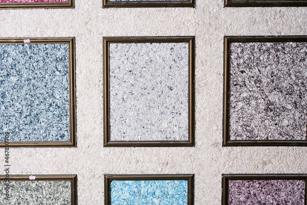Fototapeta premium Samples of colored liquid wallpaper decorative plasters in frames in construction store