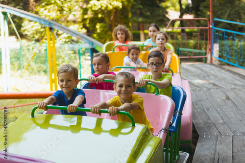 The happy kids on a roller coaster in the amusement park