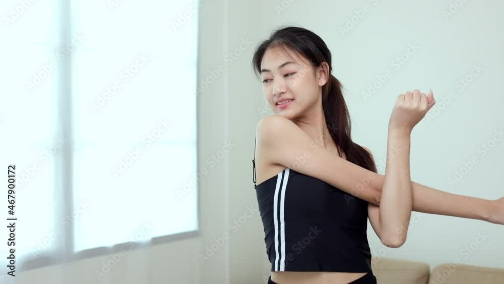Attractive asian young fitness woman stretching arms warming up before workout at home. Beautiful smiling Female wearing sportswear exercise training yoga in living room. Attractive asian young fitness woman stretching arms warming up before workout at home. Beautiful smiling Female wearing sportswear exercise training yoga in living room.