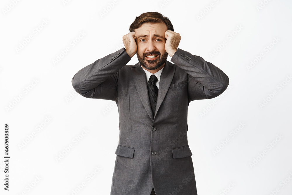Anxious and distressed businessman holding hands on head, looking in panic, having headache, big problem, standing over white background Anxious and distressed businessman holding hands on head, looking in panic, having headache, big problem, standing over white background