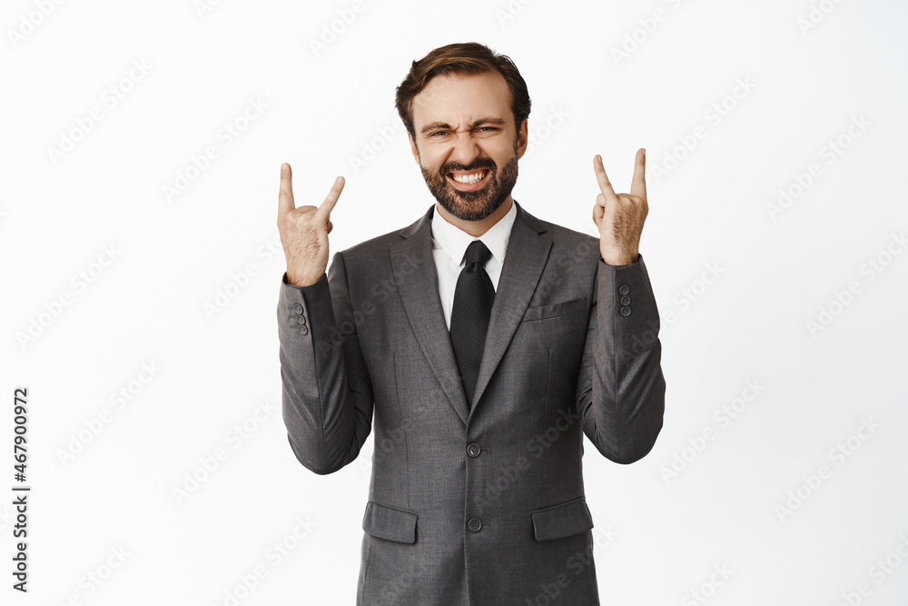 Lets rock. Happy corporate man in office suit showing horns gesture, heavy metal and smiling pleased, rejoicing, standing over white background Lets rock. Happy corporate man in office suit showing horns gesture, heavy metal and smiling pleased, rejoicing, standing over white background