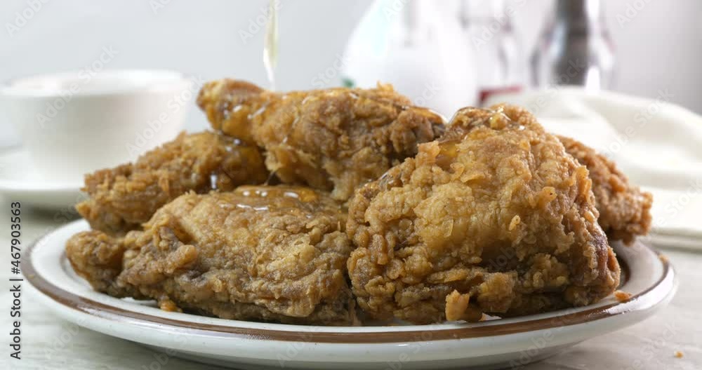 Pouring honey onto breaded fried chicken close up Pouring honey onto breaded fried chicken close up