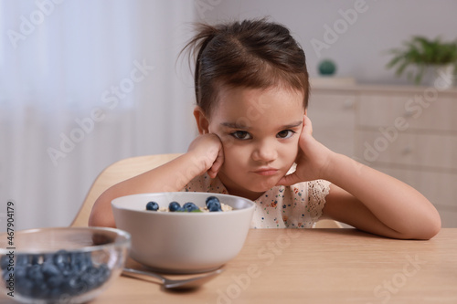 Cute little girl refusing to eat her breakfast at home photo