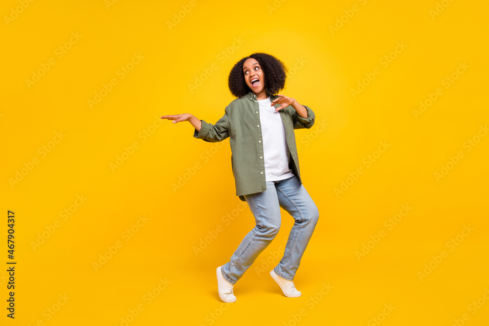 Full length photo of cute brunette millennial curvy lady dance wear shirt jeans footwear isolated on yellow color background Full length photo of cute brunette millennial curvy lady dance wear shirt jeans footwear isolated on yellow color background