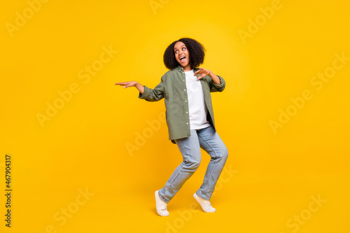 Full length photo of cute brunette millennial curvy lady dance wear shirt jeans footwear isolated on yellow color background