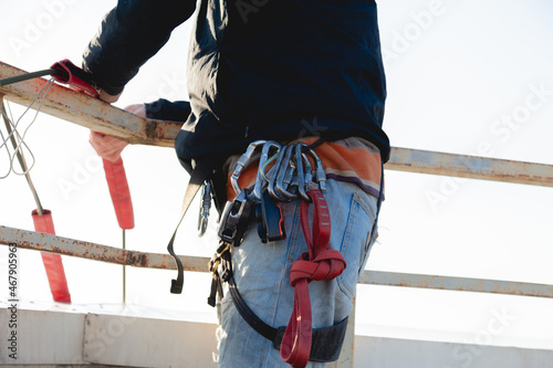 A climber in gear is getting ready to work on the roof of the building