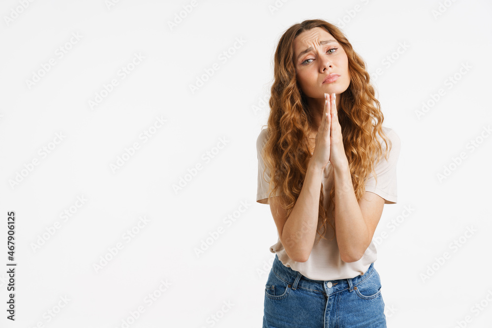 Young ginger woman in t-shirt frowning while making praying gesture Young ginger woman in t-shirt frowning while making praying gesture