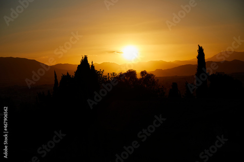 Sunset with clear sky seen from the castle of Malaga. Orange sunset. Mediterranean sea, harbor, forest and city below.