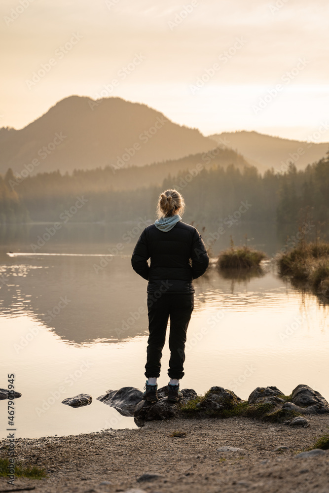 Woman is watching the sunrise over lake Hintersee in Bavaria